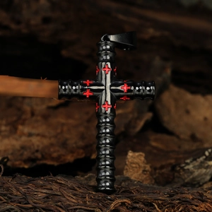 Detail of black cylinder cross pendant with red cross engraving on wood background