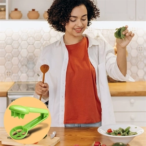Lifestyle shot of a woman using the green plastic slicer for tomatoes and grapes in a kitchen