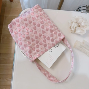 Detailed close-up of pink floral heart-embossed tote bag with simple wish label on desk