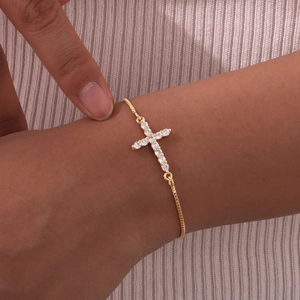 Elegant gold cross bracelet with shimmering cubic zirconia worn on a female wrist
