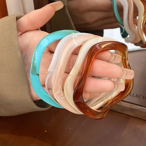 Detail of wavy resin bracelets in amber, blue and pink with artistic marbling texture