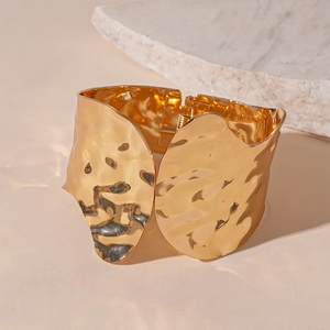 Detailed view of wide gold-plated cuff bracelet featuring textured hammered metal finish