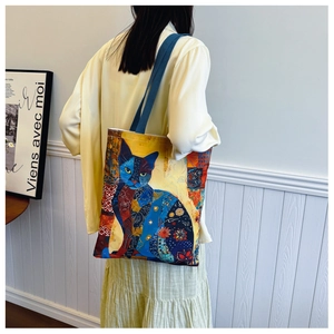 Artistic canvas tote bag with colorful cat illustrations shown on a shoulder