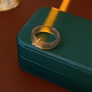 Macro view of smoky grey translucent resin ring with silver cross pendant on green box