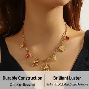 Detail view of a gold chain necklace featuring colorful cherry, flower and bear charms