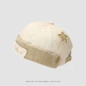 Detail of beige cotton kids docker hat featuring star patch and Britney embroidery