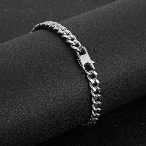 Detail of silver Cuban link bracelet with secure metal clasp on matte black stand