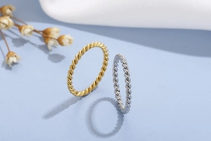 Close-up of twisted rope rings in gold and silver finish with detailed metal texture