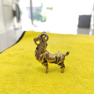 Close-up detail of vintage brass goat figurine with antique finish and curved horns