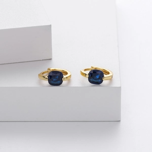 Detail of gold hoop earrings with square blue zircon stones on white display