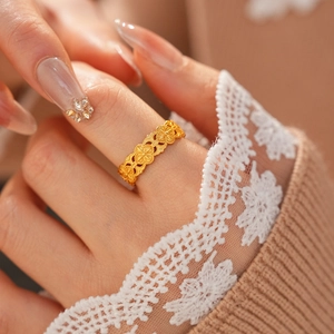 Gros plan d'une bague ouverte dorée avec des motifs ajourés de trèfles à quatre feuilles