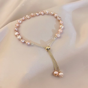 Detailed shot of pink baroque pearls with adjustable golden chain on silk fabric
