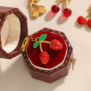 Macro detail of strawberry enamel pendant in vintage red velvet hexagon jewelry box