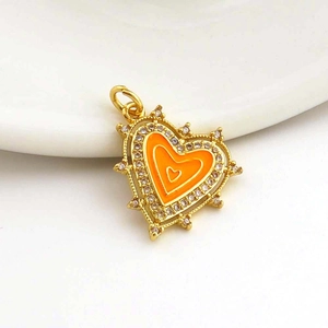 Macro shot of gold heart pendant with orange enamel and micro-set cubic zirconia border
