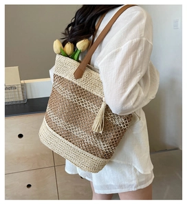 Close-up of beach straw tote bag with checkered weave, leather straps and beige tassels