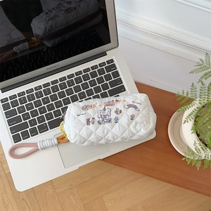 Detailed shot of white quilted stationery pouch with cartoon embroidery and wrist strap