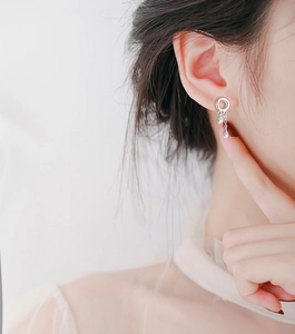 Close-up of minimalist silver water drop tassel earrings worn on a model's ear