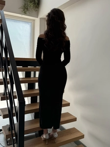 Elegant back view of slim fit black off-shoulder long dress with high heels on stairs