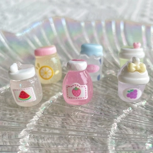 Macro view of miniature resin juice bottles with glitter and fruit charms on a glass plate