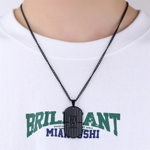 Close-up of black dog tag necklace with letter A engraving worn by a model