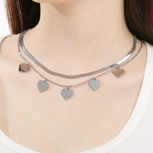 Gros plan d'un collier double épaisseur en acier inoxydable avec cinq pendentifs cœur