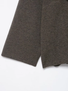 Detailed close-up of dark knit texture and ribbed cuff craftsmanship on the poncho
