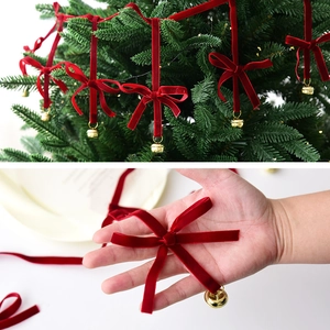 Velvet Christmas bow with golden bell ornament on tree and held by hand for scale