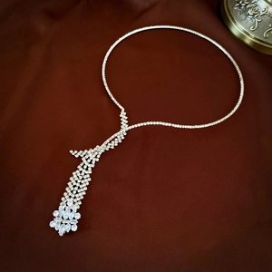 Detailed view of silver wheat tassel necklace with sparkling zircon on dark satin fabric