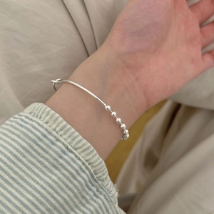 Minimalist 925 sterling silver bead bracelet worn on wrist over neutral beige fabric