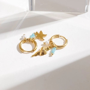 Vue détaillée de créoles dorées avec pendentifs étoile de mer et perles bleu clair