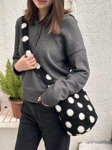 Dettaglio della borsa a secchiello in peluche a pois abbinata a un maglione in maglia
