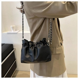 Detail of black pleated bucket bag with silver chain strap on khaki blazer outfit