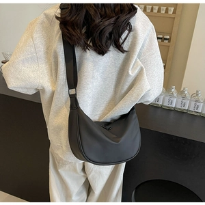 Black waterproof nylon half-moon crossbody bag shown on a model in a cafe setting
