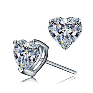 Detailed close-up of heart-shaped zircon stud earrings with three-prong silver setting
