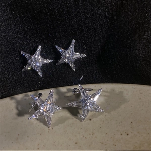 Macro shot of sparkling silver starfish earrings with cubic zirconia on black background