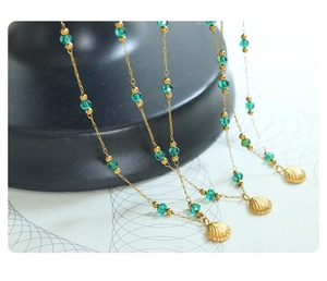 Detail of 18K gold-plated shell pendant necklaces with green crystal beads on display