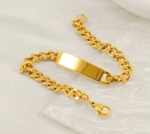 Bracelet gourmette en or 18 carats avec plaque rectangulaire sur surface en marbre