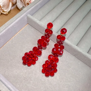 Detail of red crystal flower tassel earrings in a grey velvet jewelry gift box