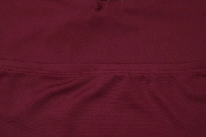 Macro detail of burgundy knit fabric with professional double-needle stitching and texture