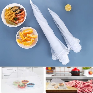 Collapsible white mesh food cover with lace trim shown folded and in use on dining table