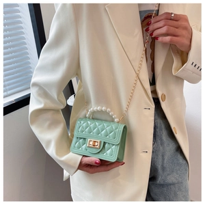 Detail of mint green quilted silicone bag featuring pearl handle and gold chain strap