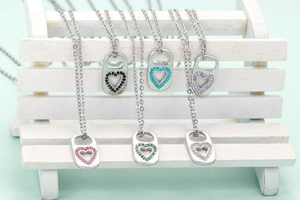Micro-inlaid zircon heart lock pendants in six colors on a white decorative bench