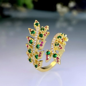 Elegant gold leaf open ring with green and red zircons in a luxury minimalist style