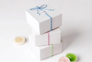 Drei weiße Geschenkboxen mit farbigen zweifarbigen Baumwollseilen und Dankeskärtchen