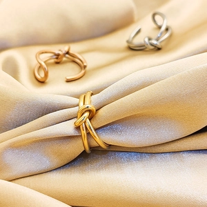 Detailed view of knot rings in gold, silver and rose gold over champagne silk fabric