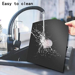 Washable Teflon gas stove protector being rinsed under water for easy cleaning