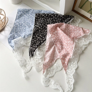 Dettaglio di sciarpe di seta floreali con bordi in pizzo bianco nei colori blu, nero e rosa