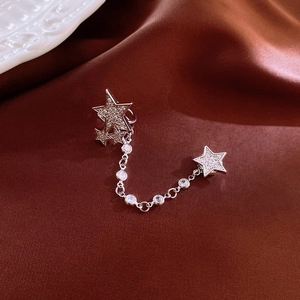 Star-shaped magnetic ear clip with zircon stones and chain on silk background