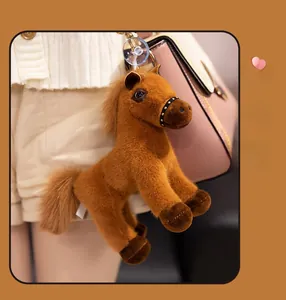 Porte-clés cheval en peluche avec rivets dorés et ventouse suspendu sur un sac rose
