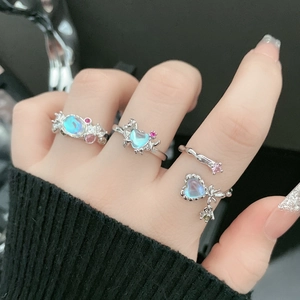 Detail of silver rings featuring blue moonstones, pink crystals, and butterfly motifs